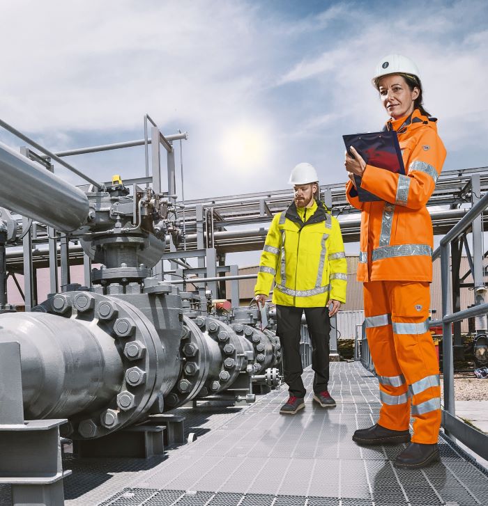 Eine Frau und ein Mann in Arbeitskleidung kontrollieren Prozesse in  der Chemieindustrie.